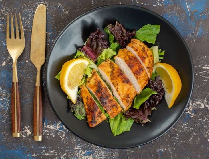 air fryer chicken breast served in plate with salad and lemon
