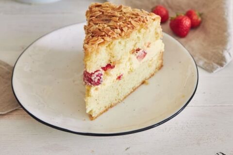 Vanilla cream cake with strawberries inside on a white table